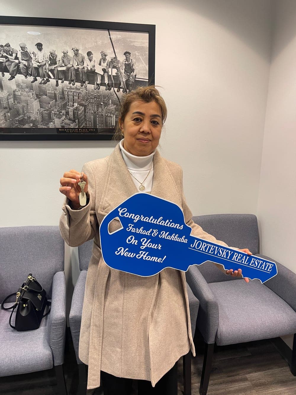 A client holding the oversized Jortevsky key congratulating Farhod and Mahbuba on their new home